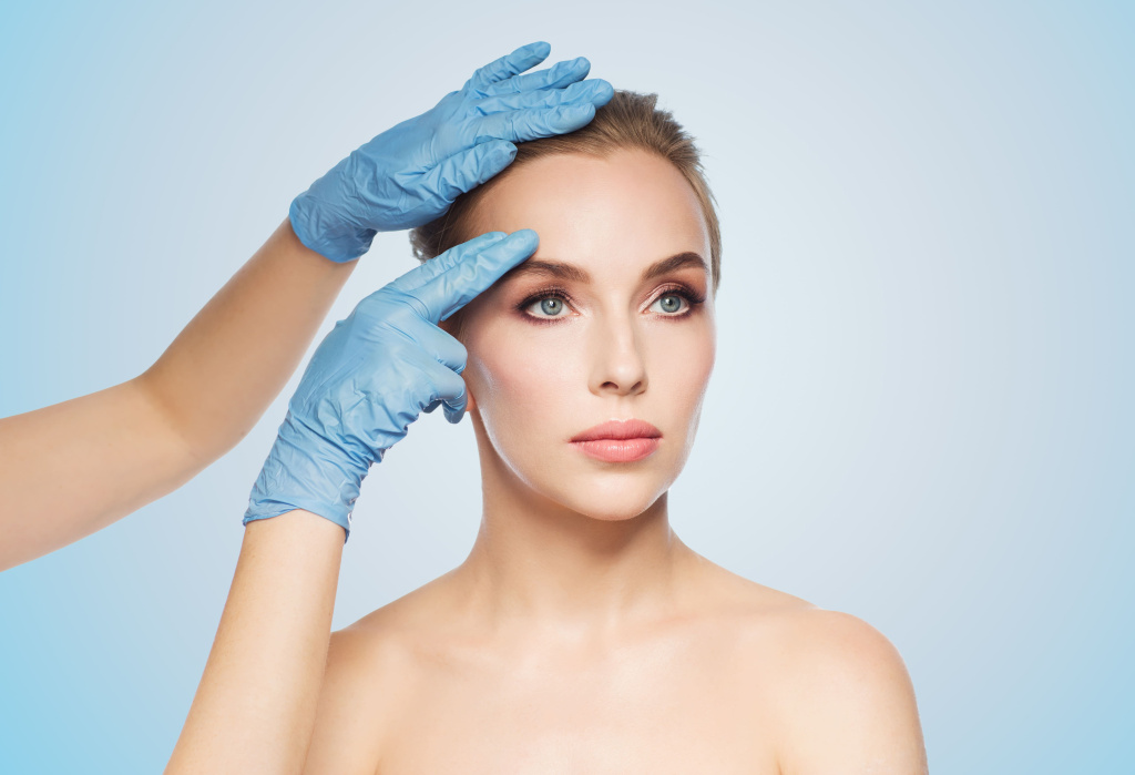 people-cosmetology-plastic-surgery-beauty-concept-surgeon-beautician-hands-touching-woman-face-blue-background.jpg